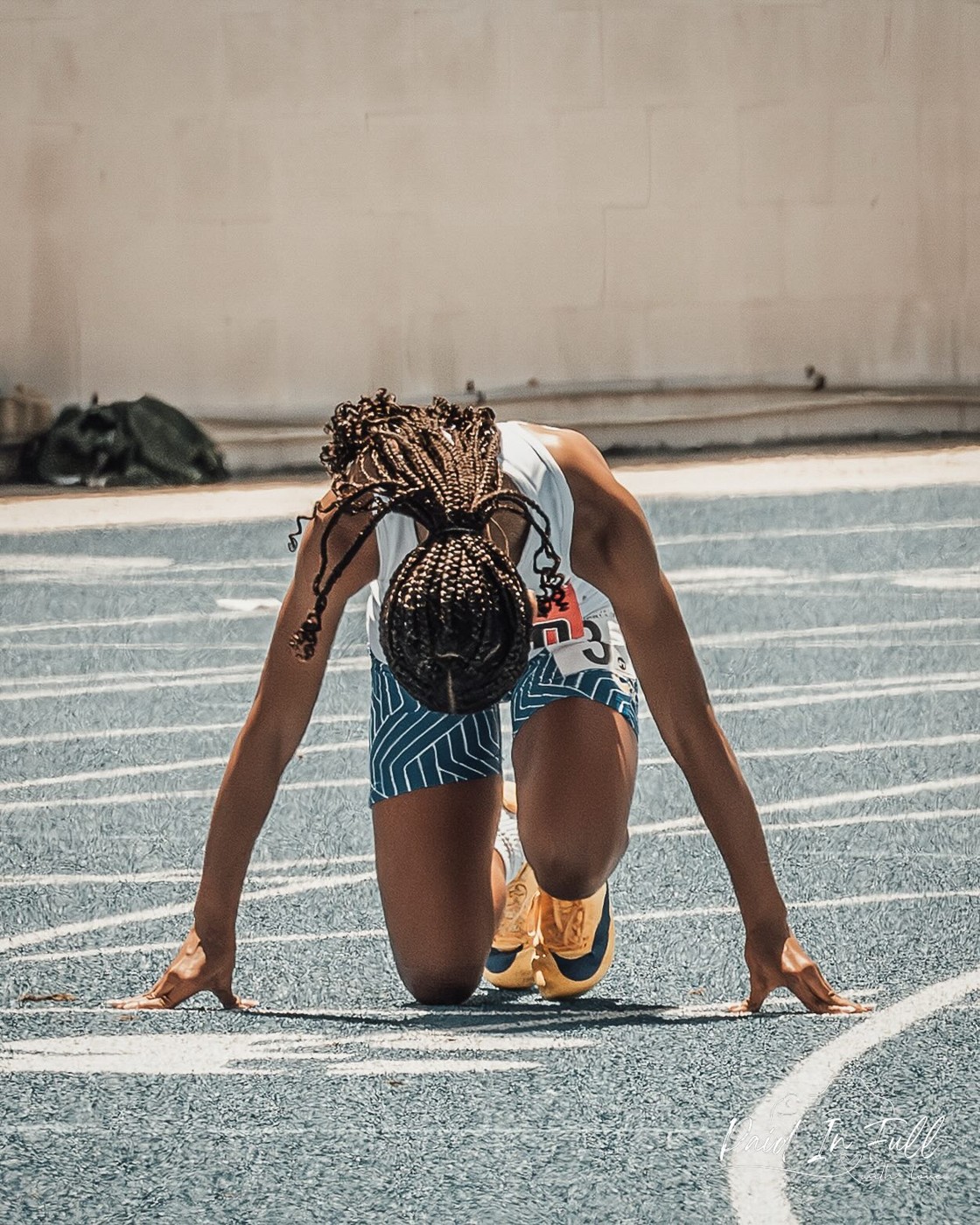 Young track athlete preparing at the starting blocks